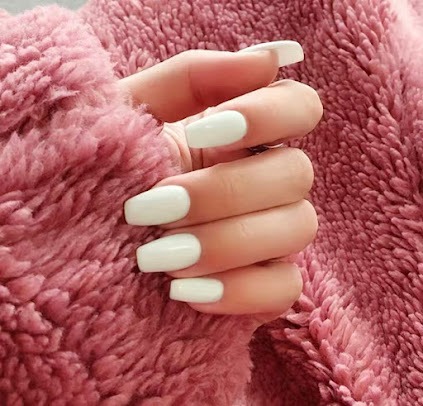 Zachte witte manicure in close-up, strak en proper afgewerkt